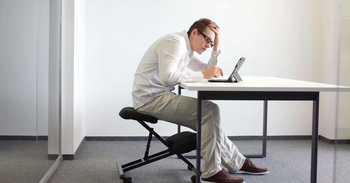 Person sitting at a work desk with a hunched back
